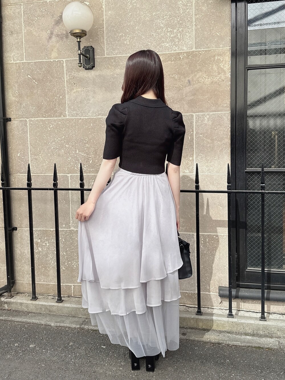 ブラック系のニット/セーター、グレー系のスカート、ブラック系のショルダーバッグを着用したレディースの春コーディネートの2枚目の写真