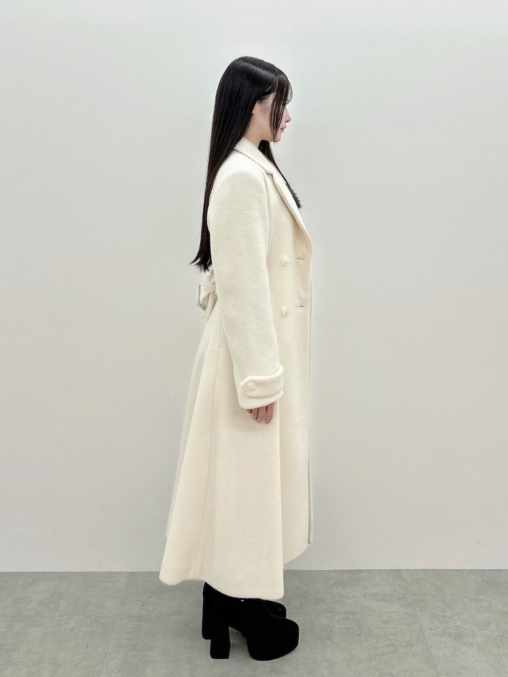 グレー系のワンピース、ホワイト系のその他アウター、ブラック系のブーツを着用したレディースの冬コーディネートの3枚目の写真