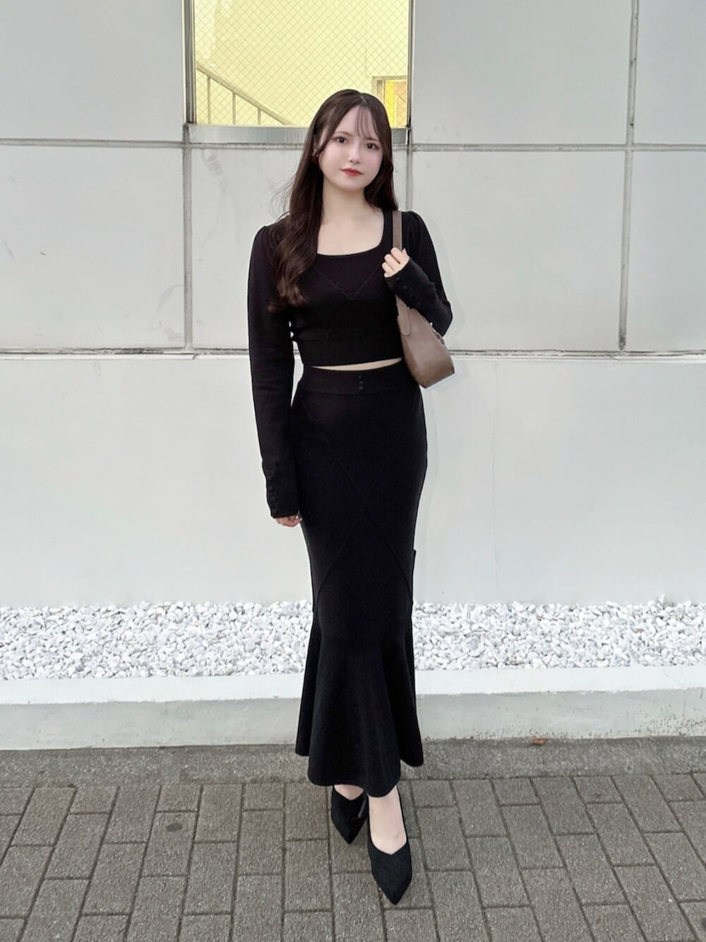 ブラウン系のショルダーバッグ、ブラック系のスカート、ブラック系のニット/セーターを着用したレディースの秋コーディネートの2枚目の写真