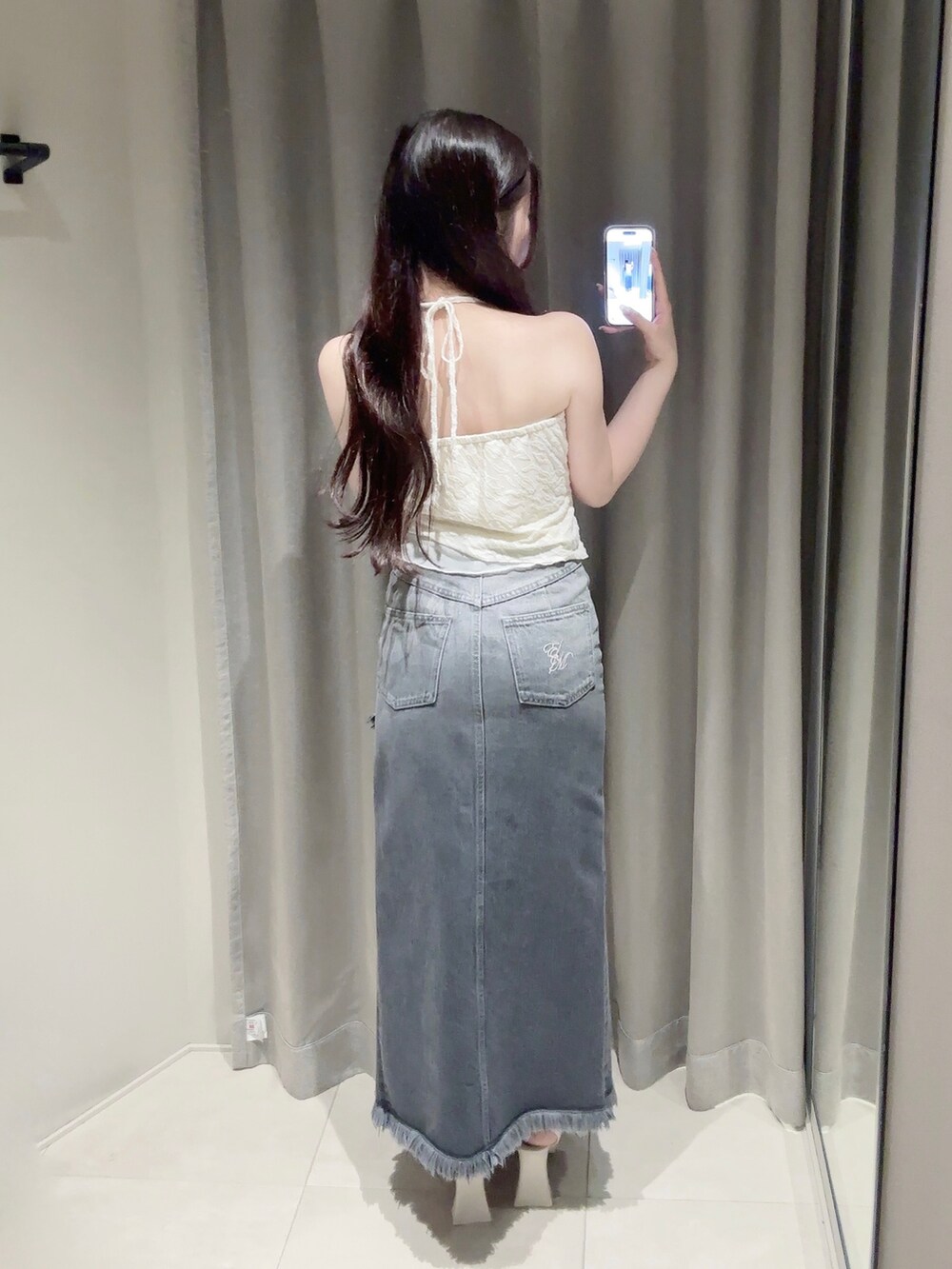 ブラック系のデニムスカート、ホワイト系のキャミソール、ホワイト系のサンダルを着用したレディースの夏コーディネートの4枚目の写真