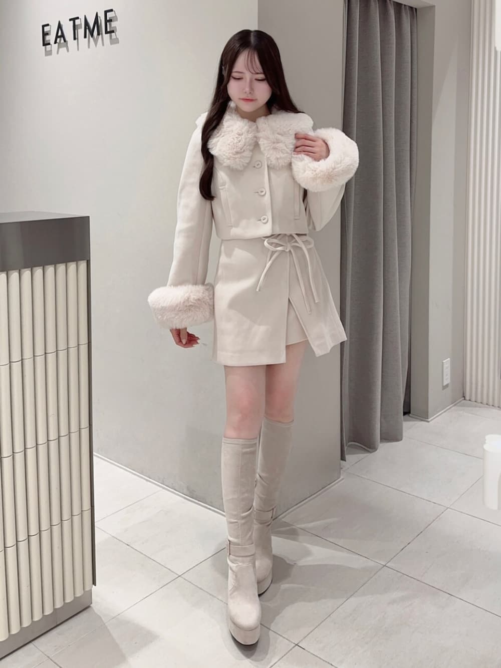 ホワイト系のブーツ、ホワイト系のスカート、ホワイト系のその他アウターを着用したレディースの秋コーディネートの2枚目の写真