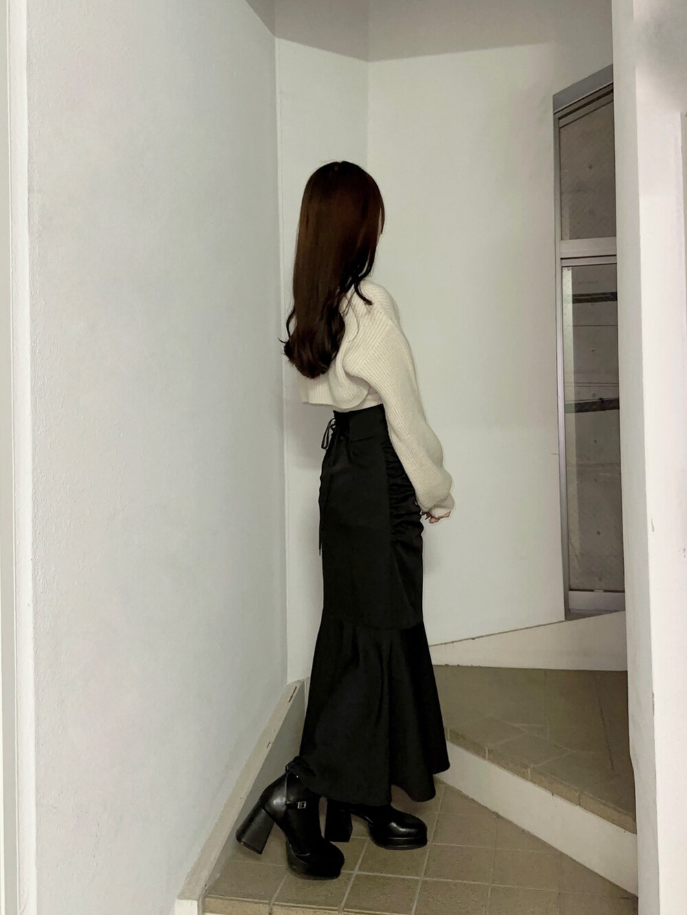 グレー系のニット/セーター、ブラック系のスカート、ブラック系のパンプスを着用したレディースの秋コーディネートの2枚目の写真