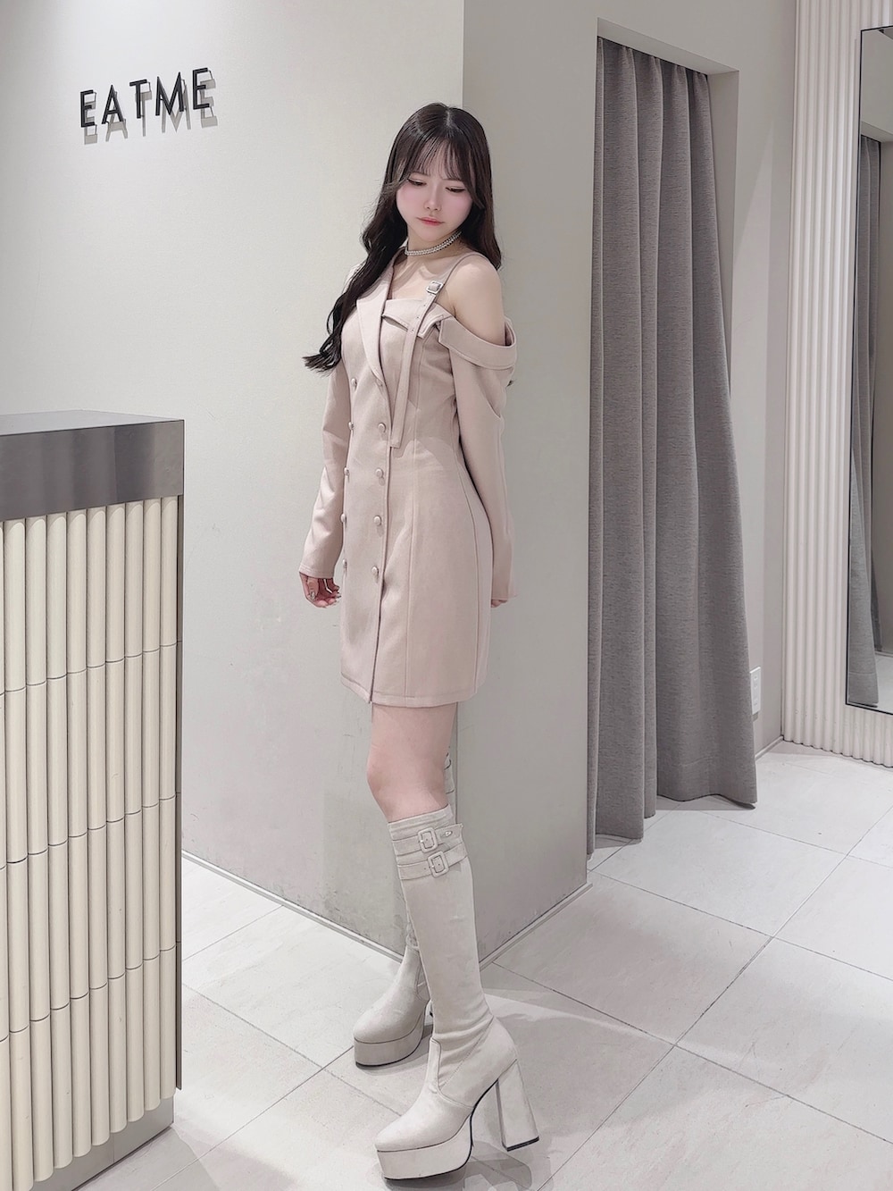 ピンク系のワンピース、ホワイト系のブーツ、シルバー系のネックレスを着用したレディースの冬コーディネートの2枚目の写真