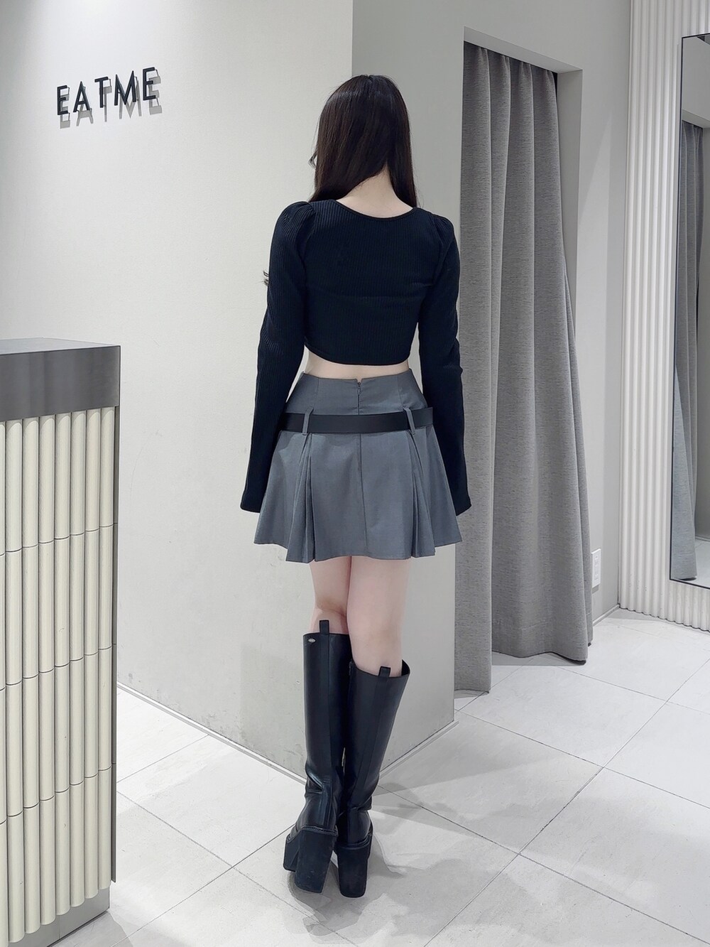 ブラック系のTシャツ/カットソー、グレー系のスカート、ブラック系のブーツを着用したレディースの冬コーディネートの4枚目の写真