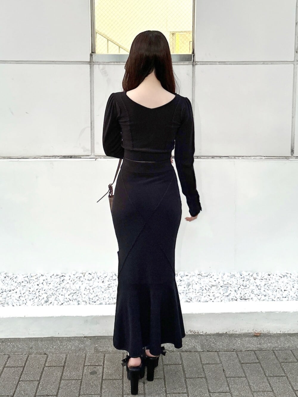 ブラウン系のショルダーバッグ、ブラック系のスカート、ブラック系のニット/セーターを着用したレディースの秋コーディネートの4枚目の写真