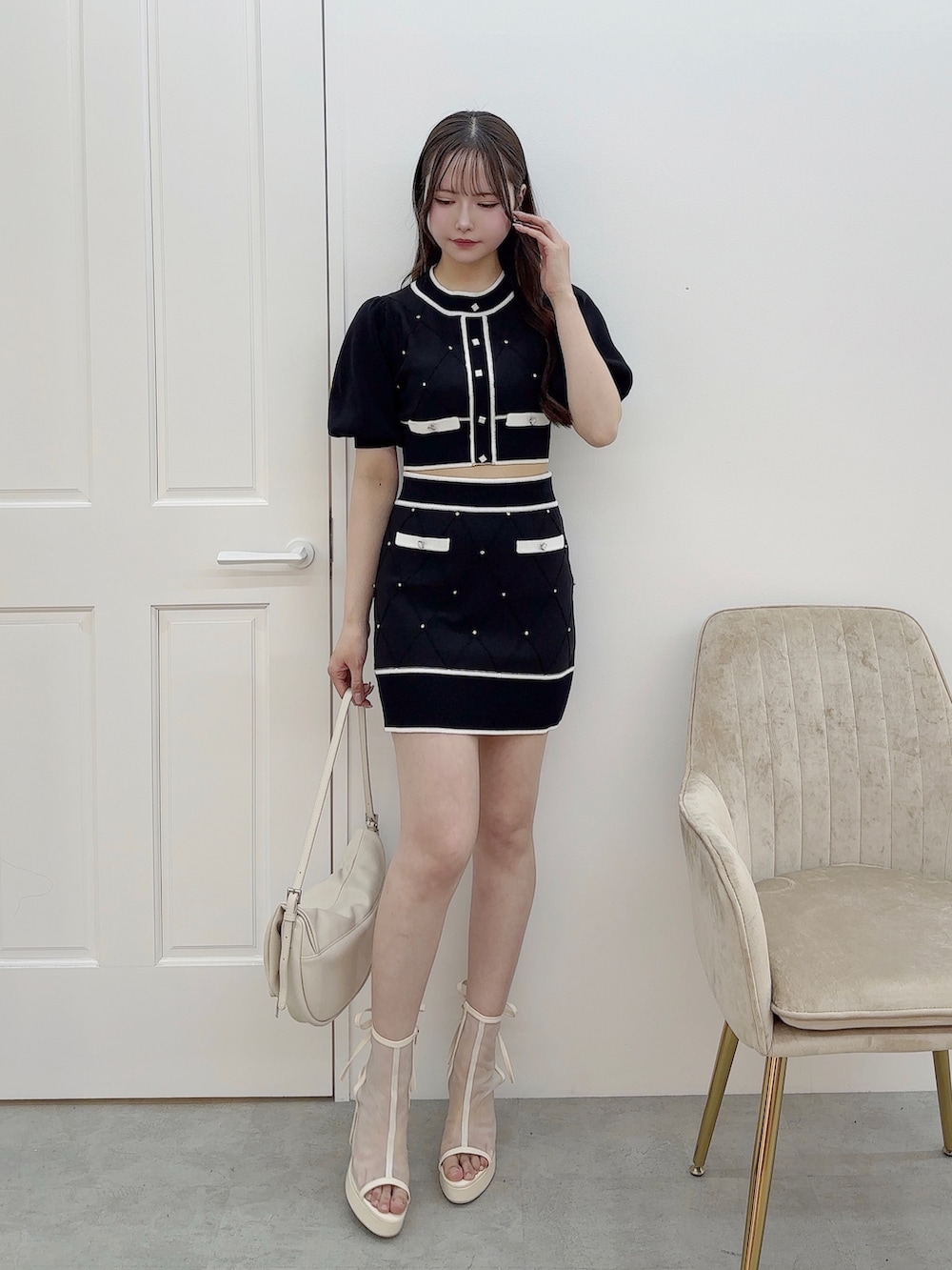 ブラック系のニット/セーター、ブラック系のスカート、ホワイト系のショルダーバッグを着用したレディースの冬コーディネートの2枚目の写真