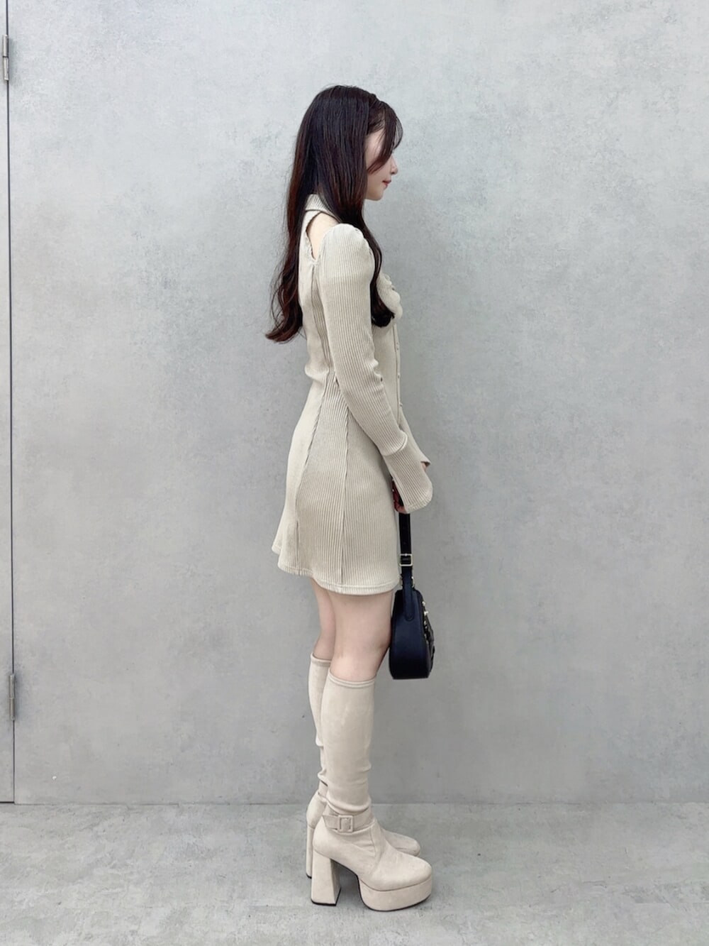 ブラック系のショルダーバッグ、ベージュ系のワンピース、ホワイト系のブーツを着用したレディースの秋コーディネートの3枚目の写真