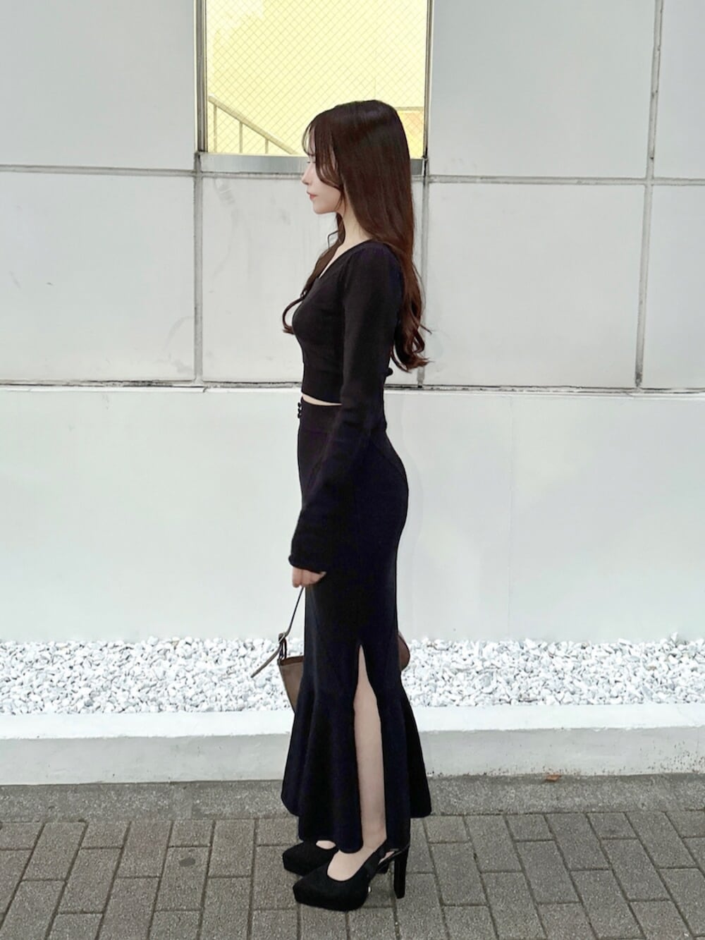 ブラウン系のショルダーバッグ、ブラック系のスカート、ブラック系のニット/セーターを着用したレディースの秋コーディネートの3枚目の写真