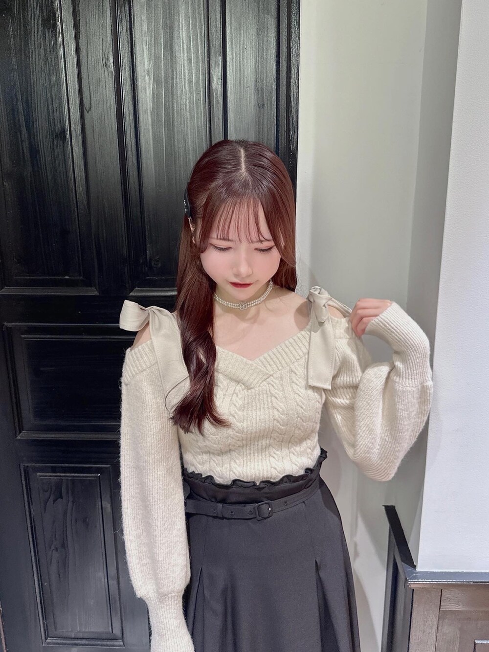 ホワイト系のニット/セーター、ブラック系のパンプス、ブラック系のジャンパースカートを着用したレディースの秋コーディネートの4枚目の写真