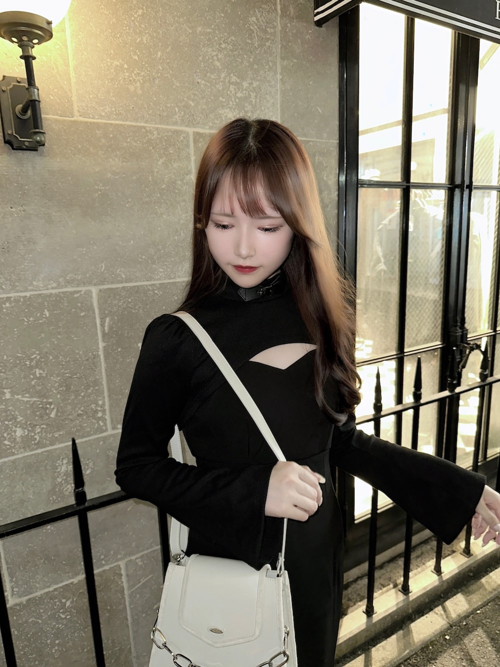 ブラック系のワンピース、ホワイト系のショルダーバッグ、ブラック系のブーツを着用したレディースの秋コーディネートの3枚目の写真