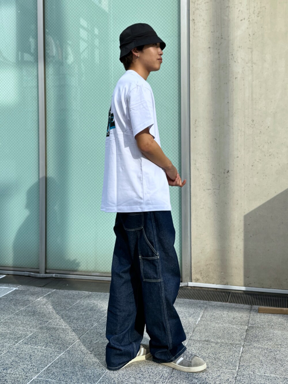 ホワイト系のTシャツ/カットソー、ブルー系のデニムパンツ、ブラック系のハットを着用したメンズの春コーディネートの4枚目の写真