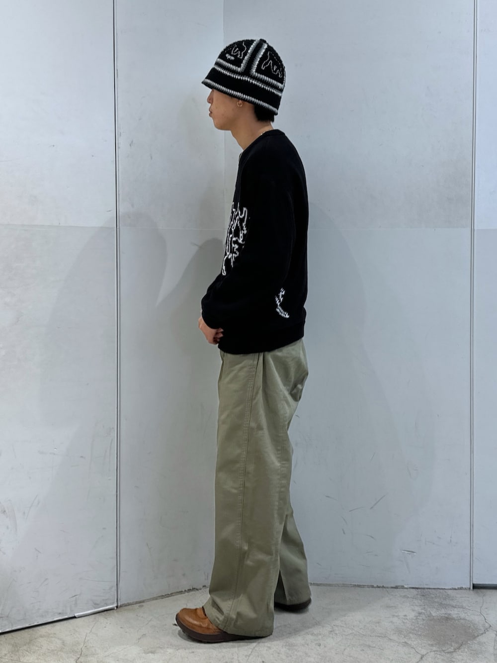 ブラック系のニット/セーター、グリーン系のチノパンツ、ブラック系のハットを着用したメンズの春コーディネートの2枚目の写真
