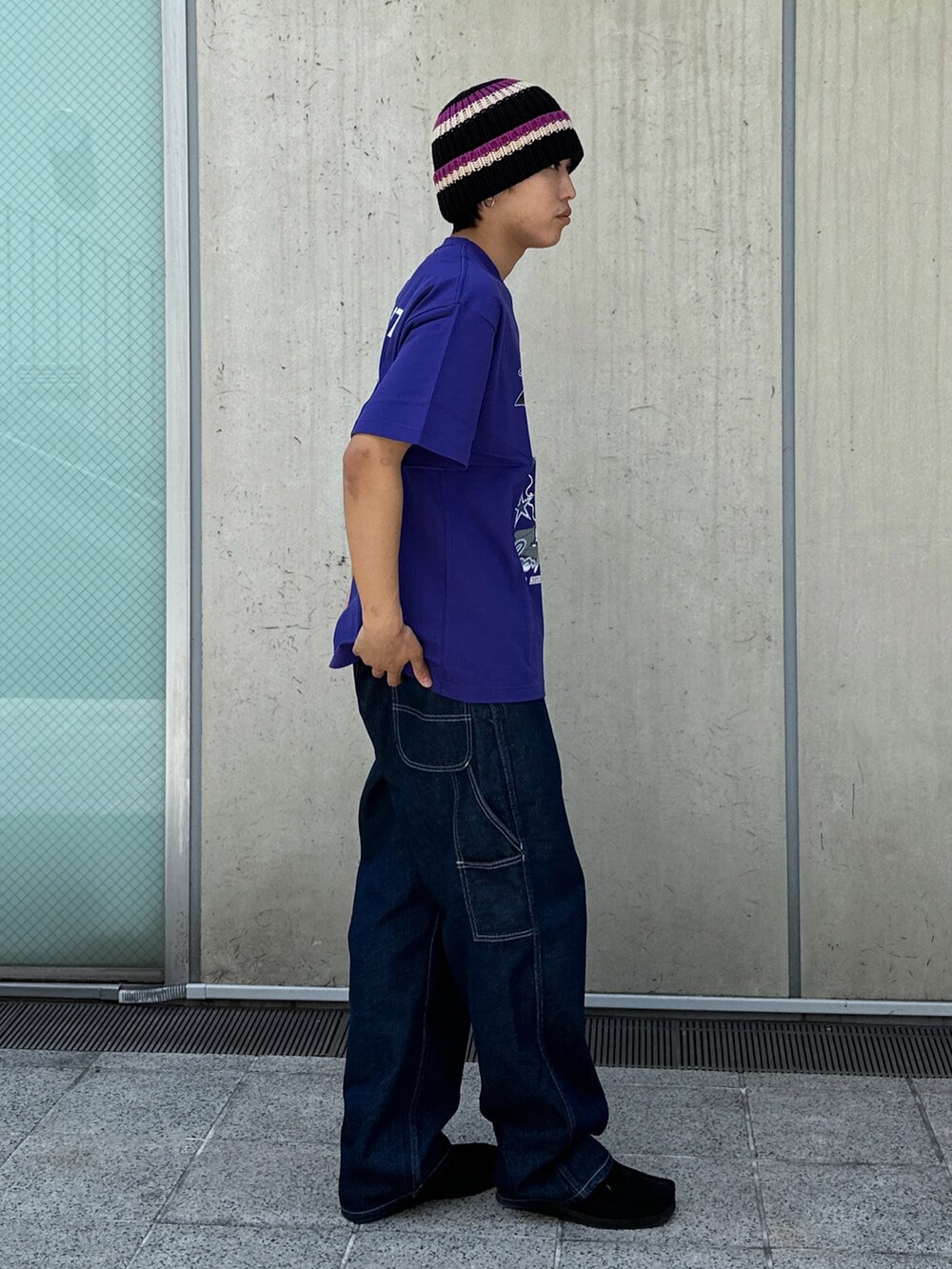 ブルー系のデニムパンツ、パープル系のTシャツ/カットソー、ブラック系のニットキャップ/ビーニーを着用したメンズの春コーディネートの4枚目の写真