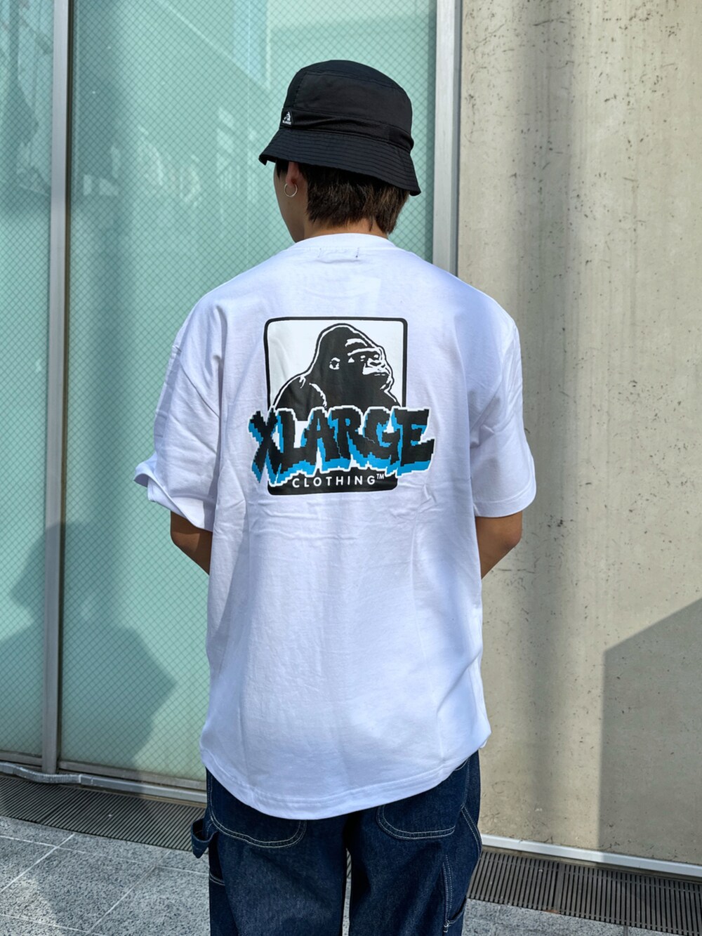 ホワイト系のTシャツ/カットソー、ブルー系のデニムパンツ、ブラック系のハットを着用したメンズの春コーディネートの5枚目の写真