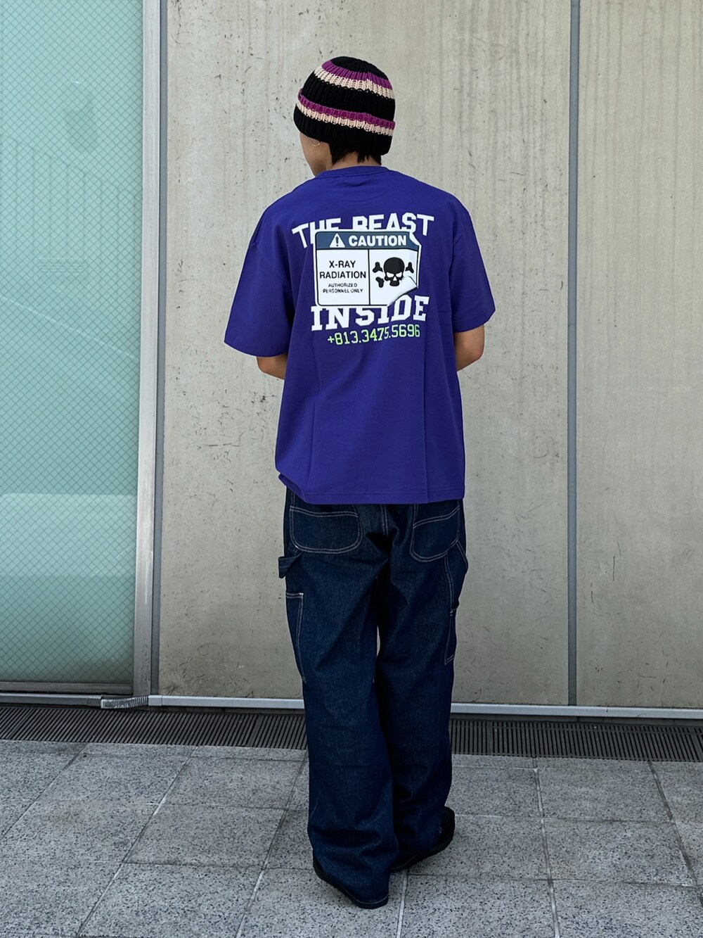 ブルー系のデニムパンツ、パープル系のTシャツ/カットソー、ブラック系のニットキャップ/ビーニーを着用したメンズの春コーディネートの3枚目の写真