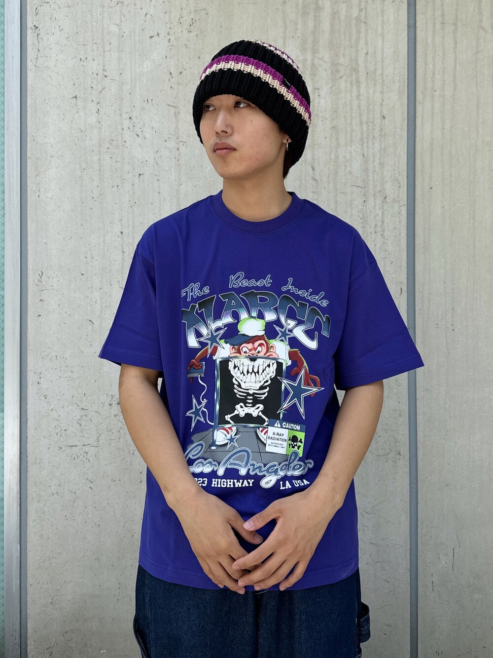 ブルー系のデニムパンツ、パープル系のTシャツ/カットソー、ブラック系のニットキャップ/ビーニーを着用したメンズの春コーディネートの5枚目の写真