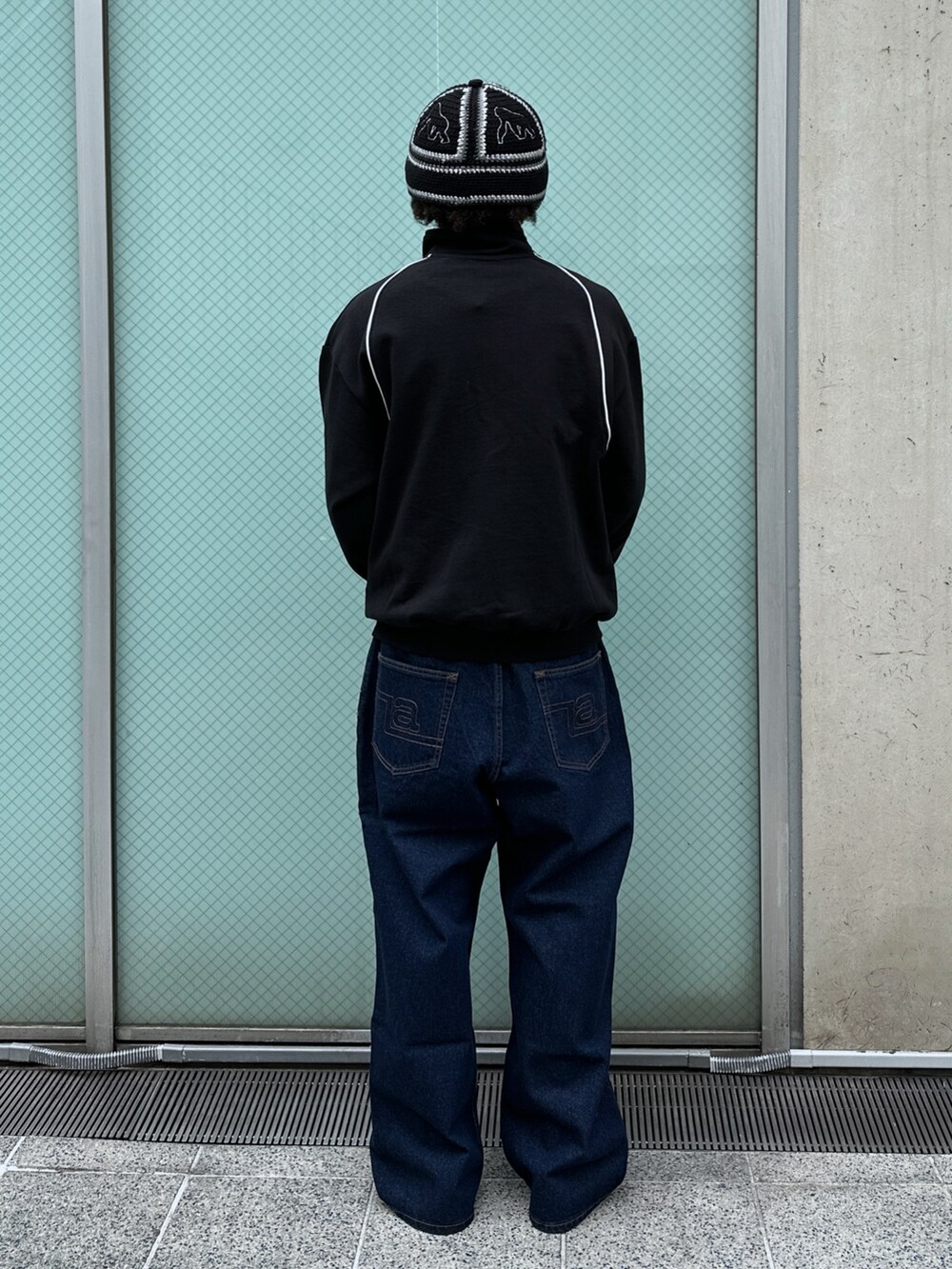 ブラック系のスウェット、ブルー系のデニムパンツを着用したメンズの冬コーディネートの3枚目の写真