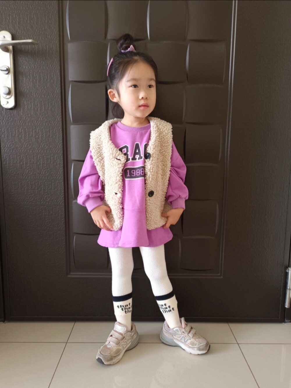 パープル系のTシャツ/カットソー、ベージュ系のその他アウター、ピンク系のスニーカーを着用したキッズの冬コーディネートの2枚目の写真