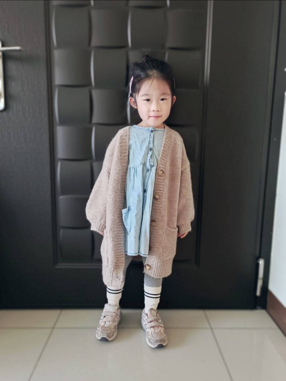 ブルー系のシャツワンピース、ピンク系のスニーカー、ベージュ系のノーカラージャケットを着用したキッズの冬コーディネートの3枚目の写真