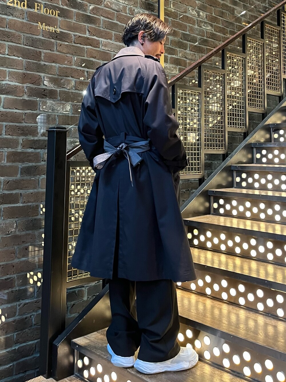 グレー系のトレンチコート、ホワイト系のニット/セーター、ブラック系のその他パンツを着用したメンズの秋コーディネートの3枚目の写真