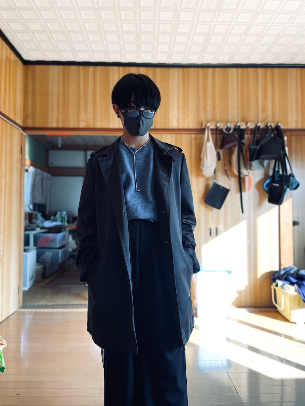 ブラウン系のチェスターコート、ブルー系のニット/セーター、ブラック系のスラックスを着用したメンズの冬コーディネートの2枚目の写真