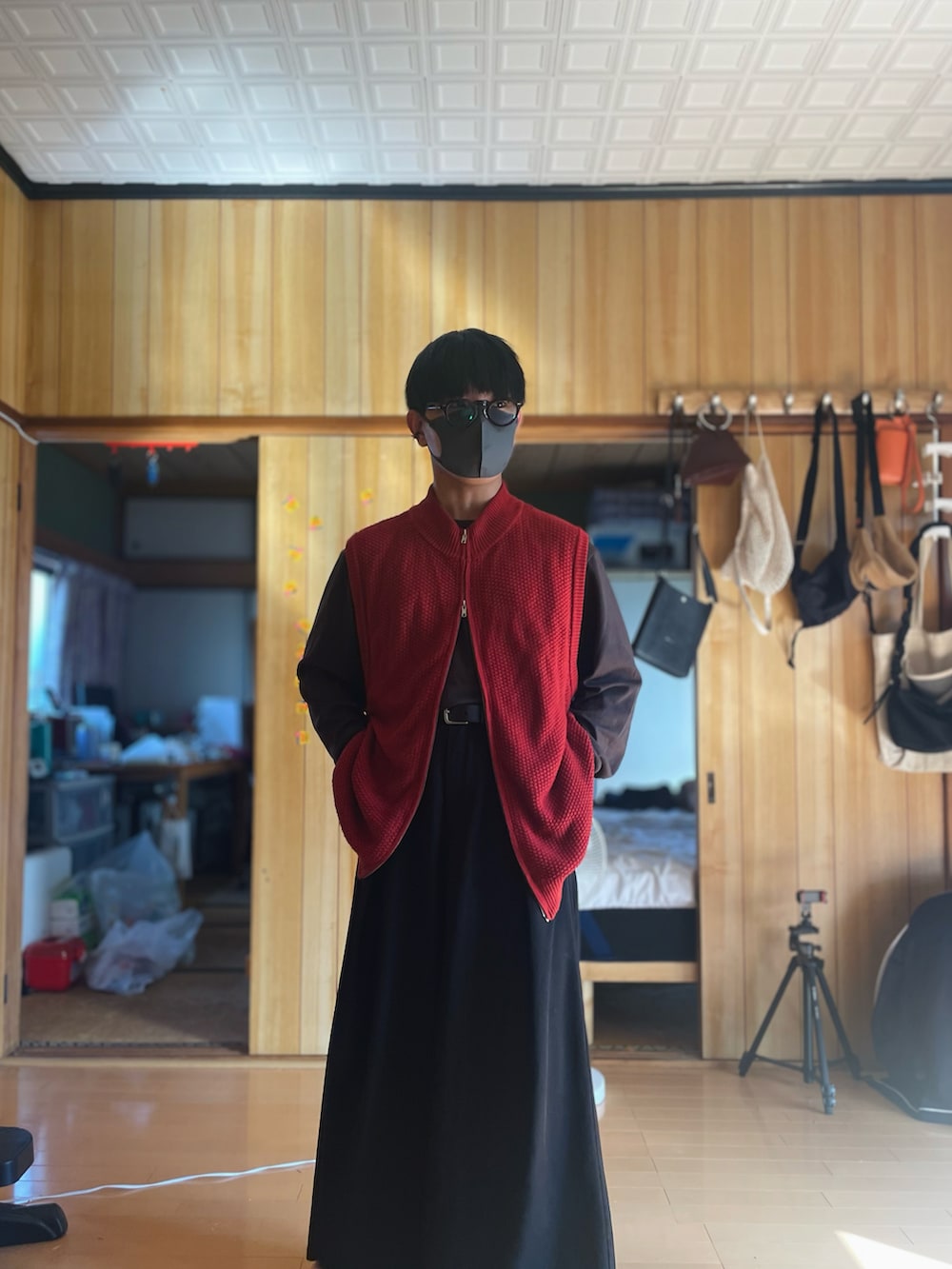 レッド系のベスト、ブラウン系のTシャツ/カットソー、ブラック系のスラックスを着用したメンズの秋コーディネートの4枚目の写真