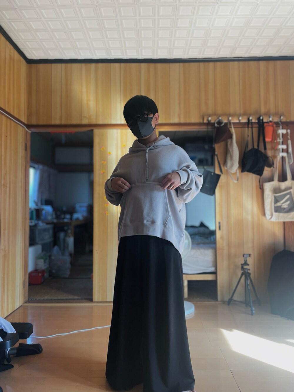 グレー系のパーカー、ブラック系のスラックス、レッド系のサングラスを着用したメンズの秋コーディネートの2枚目の写真