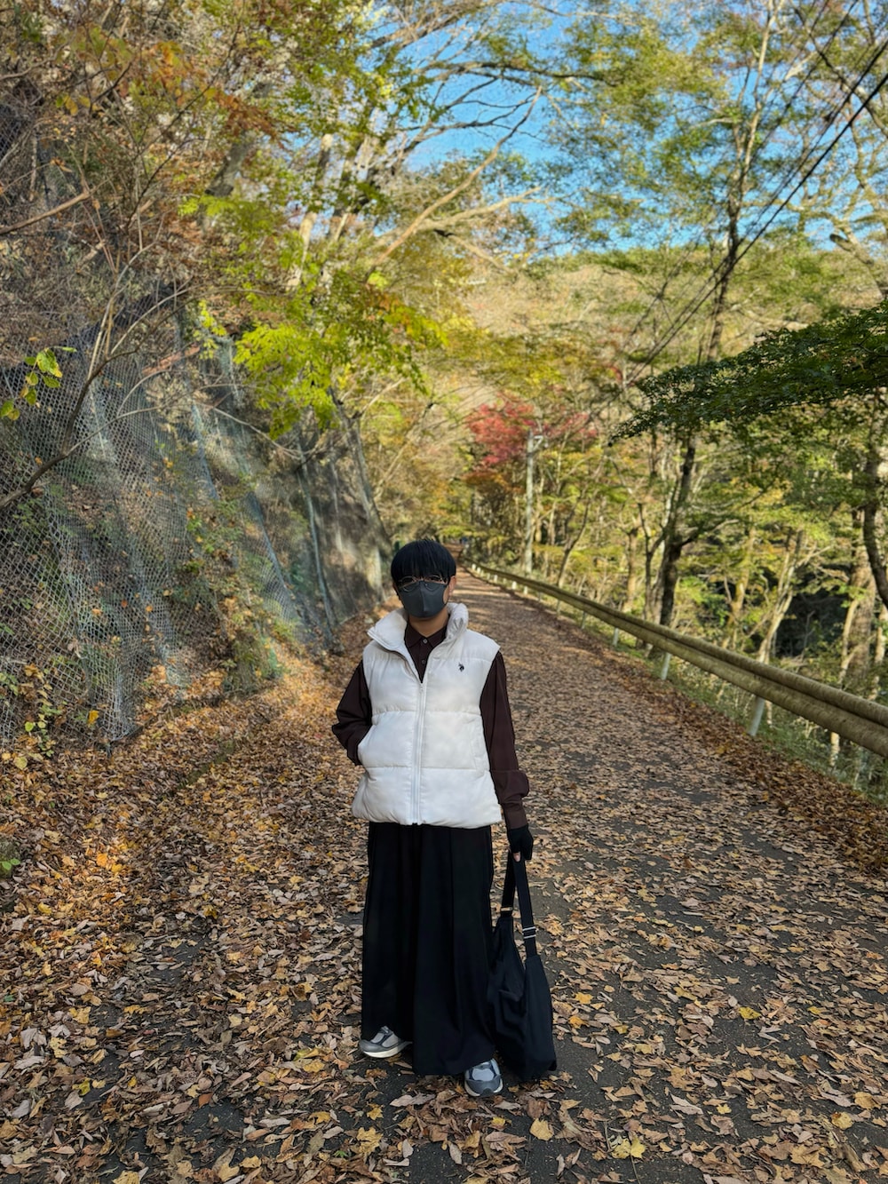 ホワイト系のダウンベスト、ブラウン系のシャツ/ブラウス、ブラック系のスラックスを着用したメンズの秋コーディネートの3枚目の写真