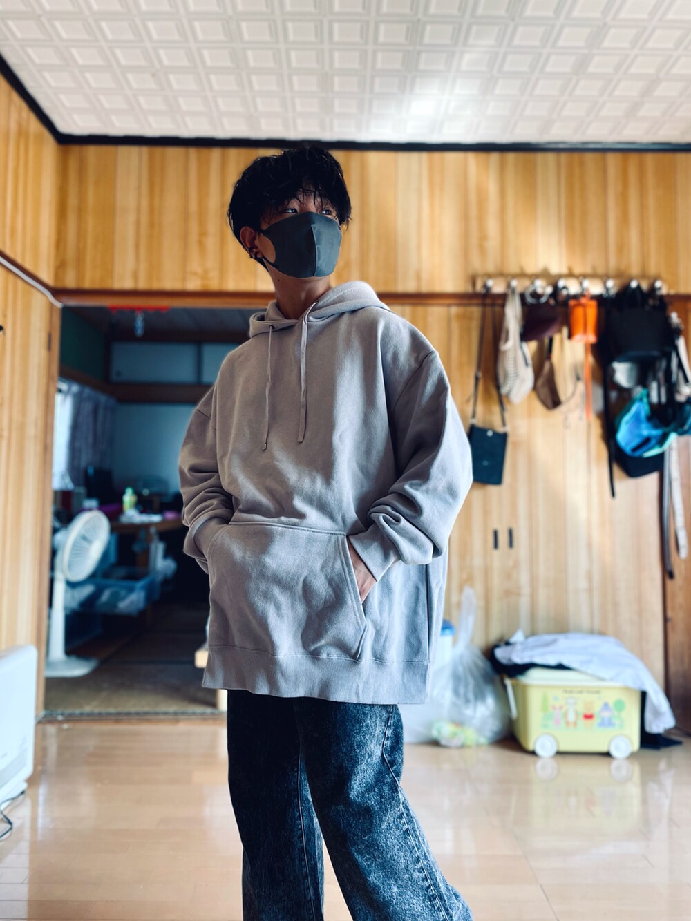 グレー系のパーカー、ブラック系のデニムパンツ、ブラック系のピアス（両耳用）を着用したメンズの秋コーディネートの2枚目の写真