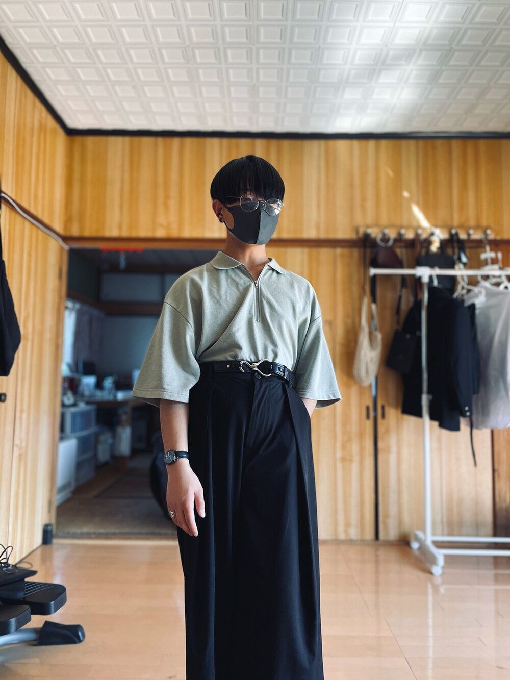 グリーン系のポロシャツ、ブラック系のスラックス、ブラウン系のチェスターコートを着用したメンズの春コーディネートの4枚目の写真