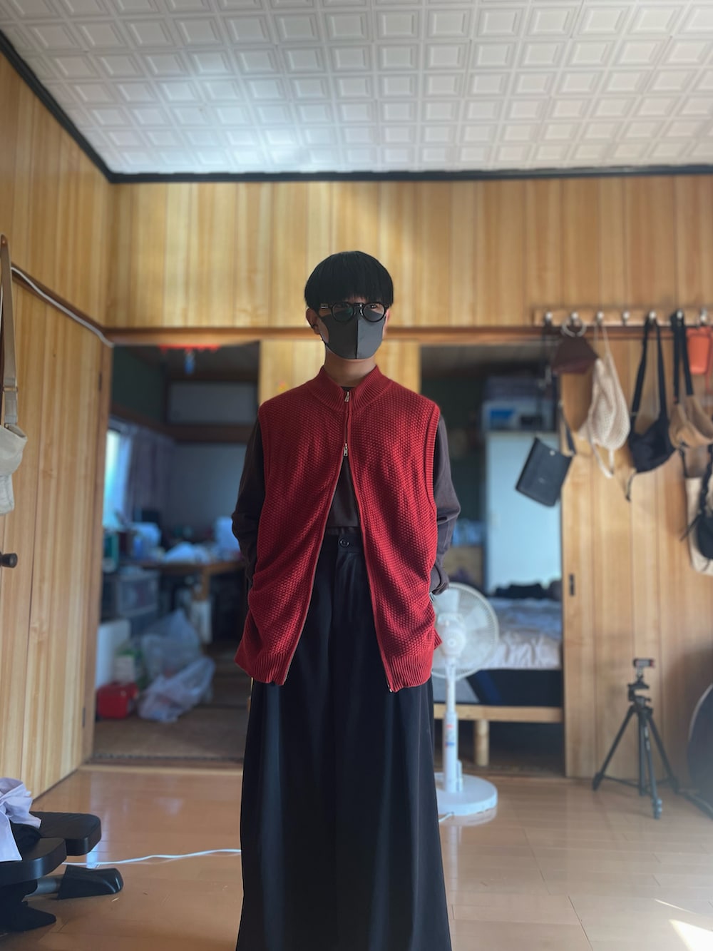 レッド系のベスト、ブラウン系のTシャツ/カットソー、ブラック系のスラックスを着用したメンズの秋コーディネートの3枚目の写真