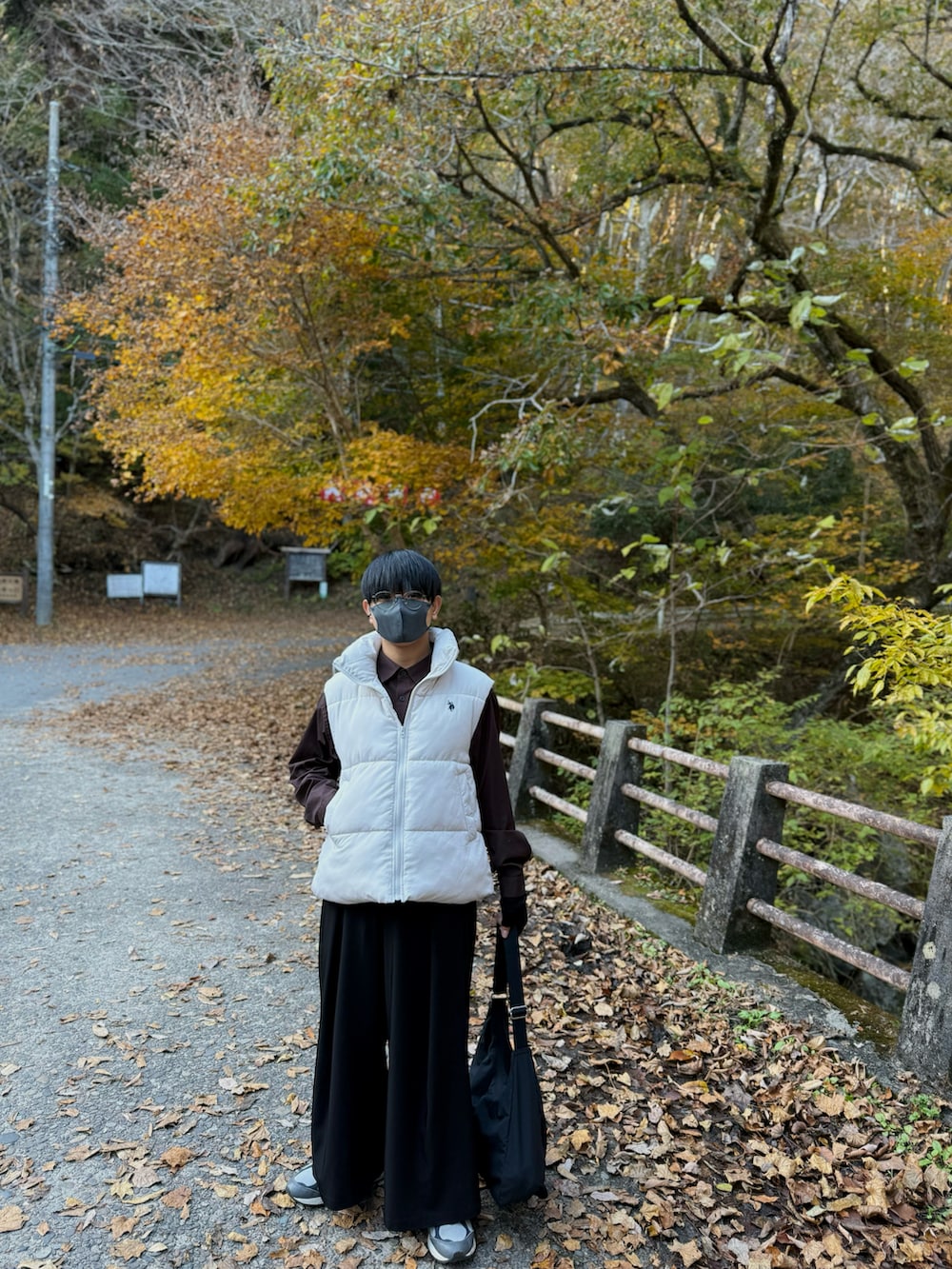 ホワイト系のダウンベスト、ブラウン系のシャツ/ブラウス、ブラック系のスラックスを着用したメンズの秋コーディネートの2枚目の写真