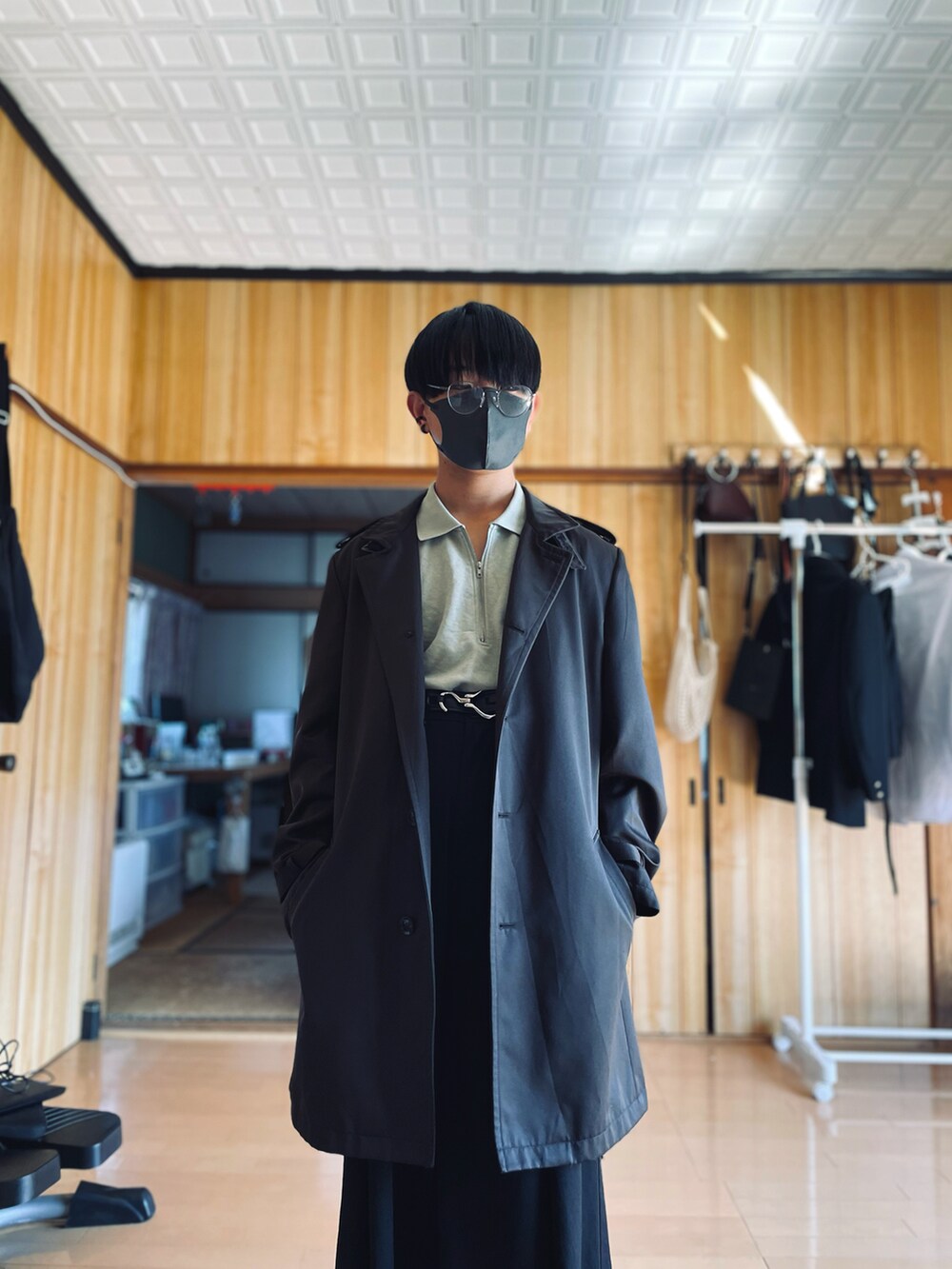 グリーン系のポロシャツ、ブラック系のスラックス、ブラウン系のチェスターコートを着用したメンズの春コーディネートの2枚目の写真