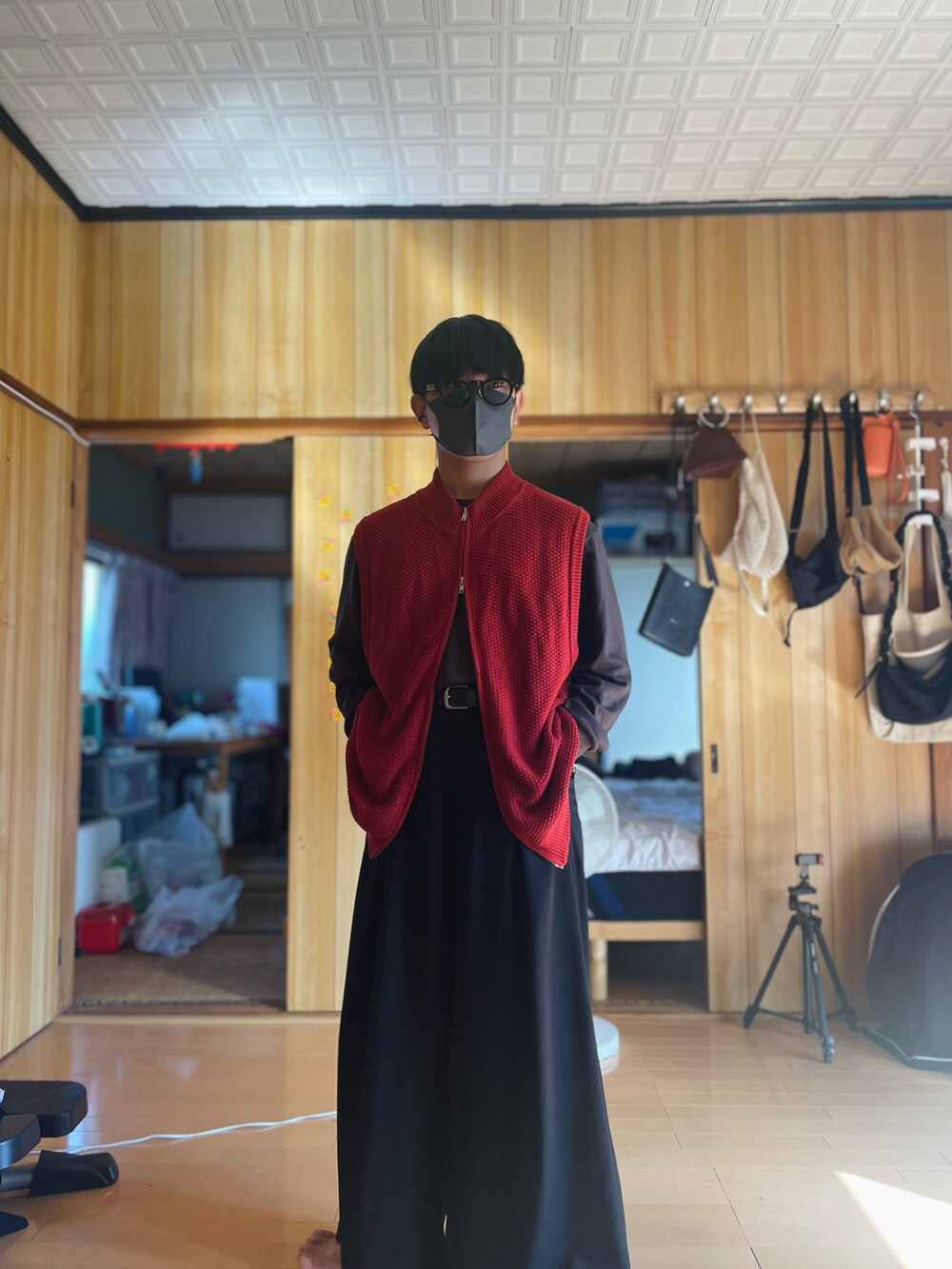 レッド系のベスト、ブラウン系のTシャツ/カットソー、ブラック系のスラックスを着用したメンズの秋コーディネートの2枚目の写真