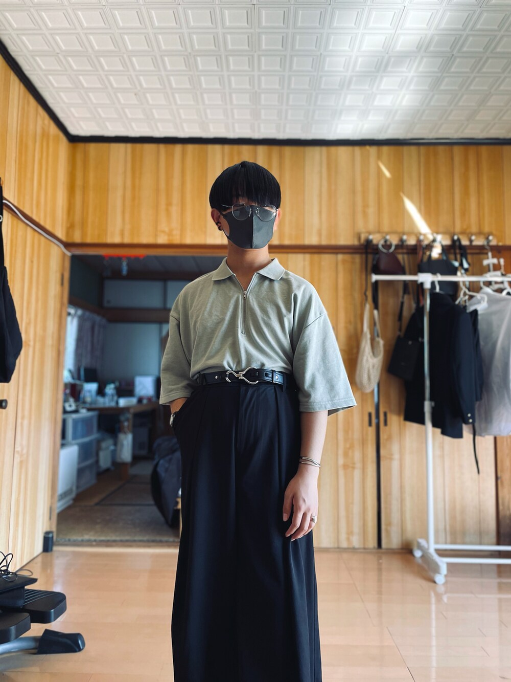 グリーン系のポロシャツ、ブラック系のスラックス、ブラウン系のチェスターコートを着用したメンズの春コーディネートの3枚目の写真