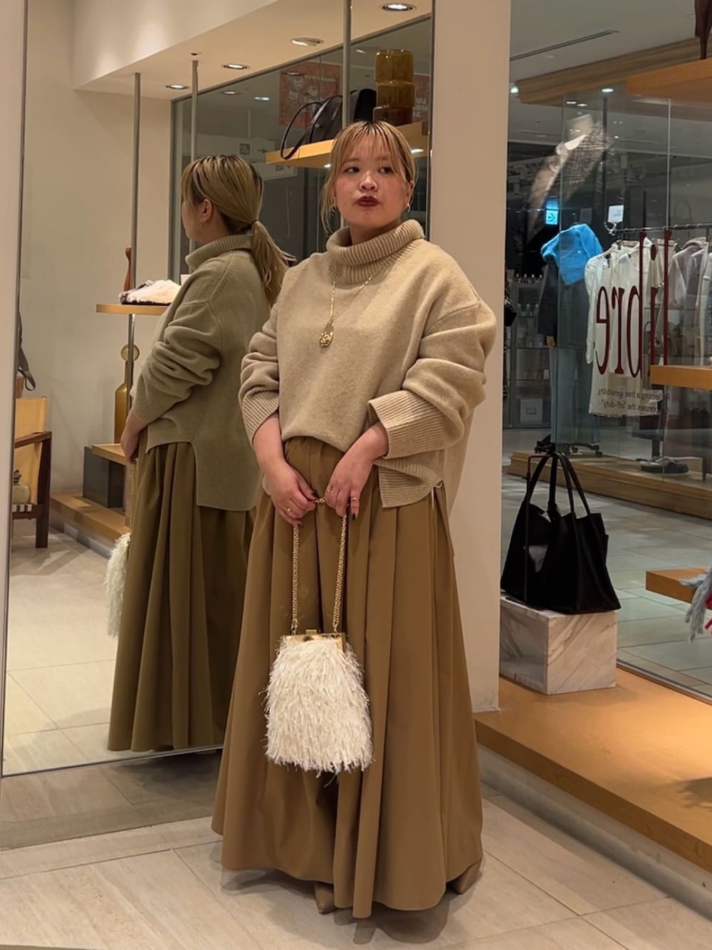 ベージュ系のニット/セーター、イエロー系のスカート、ホワイト系のショルダーバッグを着用したレディースの秋コーディネートの3枚目の写真