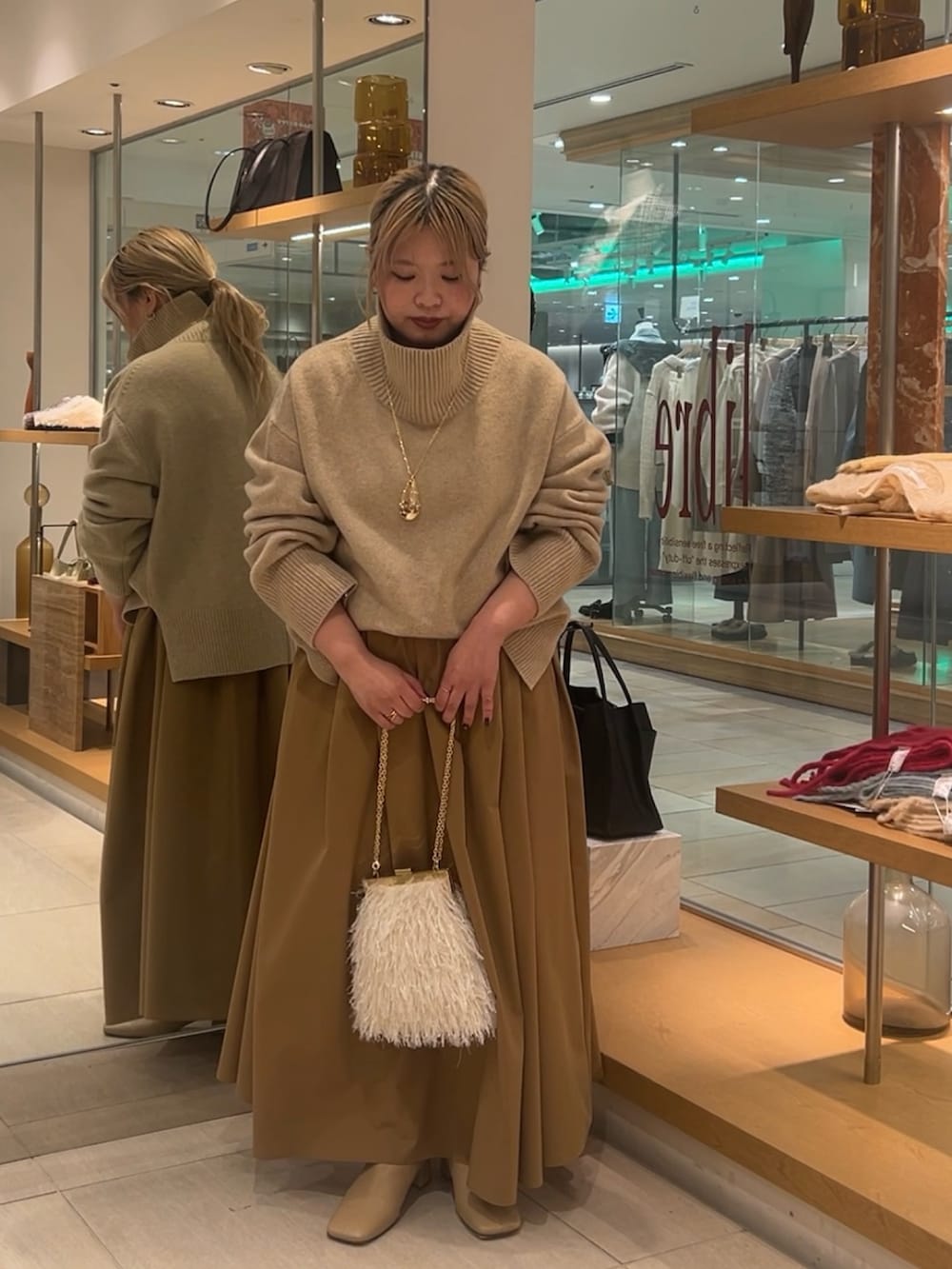 ベージュ系のニット/セーター、イエロー系のスカート、ホワイト系のショルダーバッグを着用したレディースの秋コーディネートの4枚目の写真