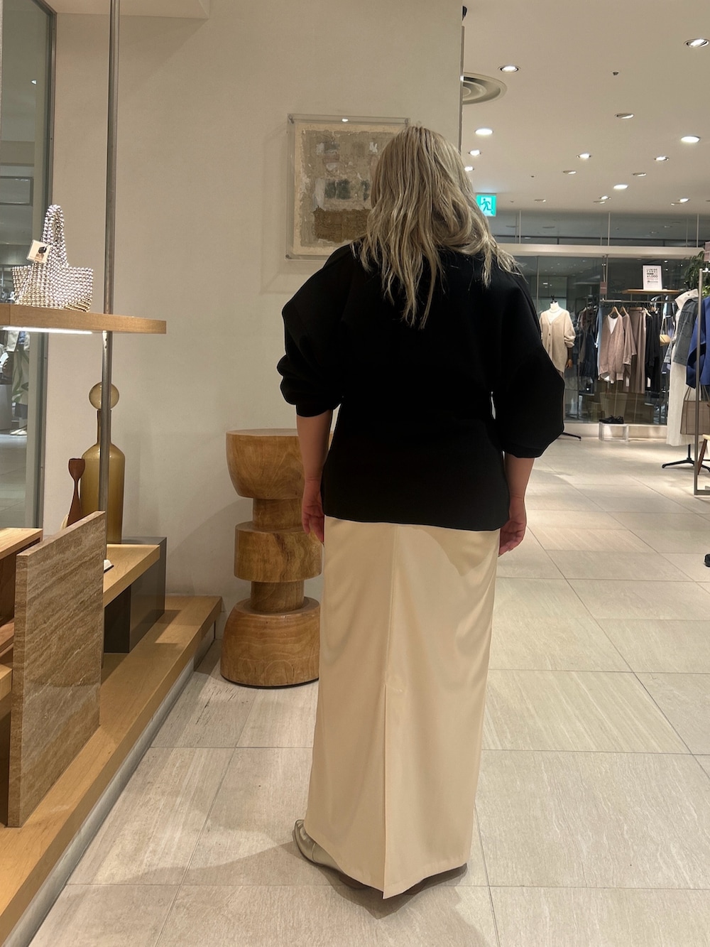 ブラック系のカーディガン/ボレロ、ホワイト系のスカート、ゴールド系のスリッポンを着用したレディースの春コーディネートの2枚目の写真