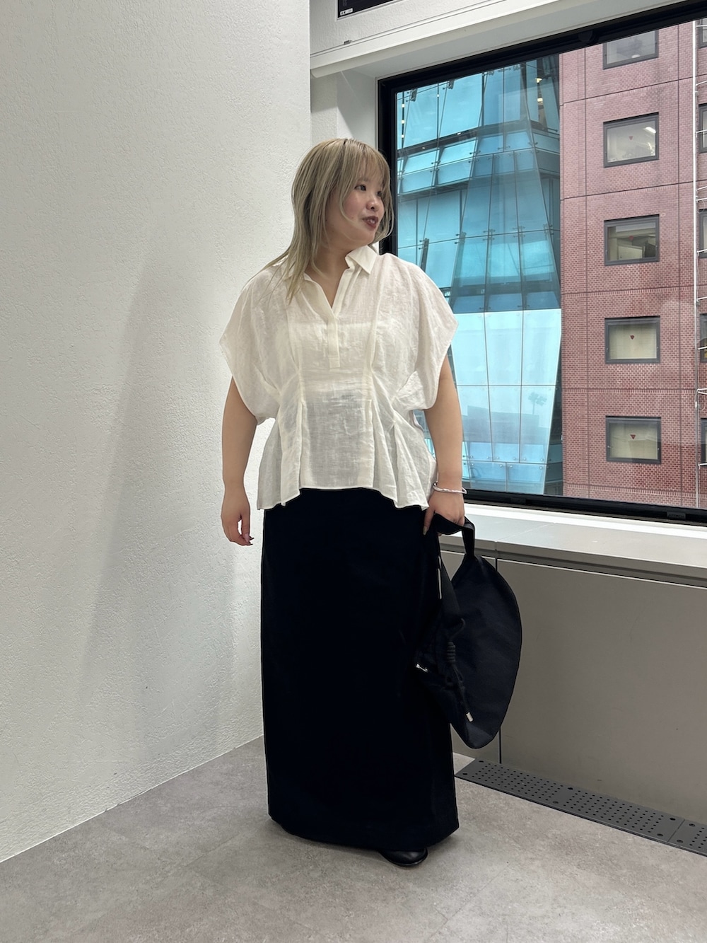 ブラック系のショルダーバッグ、ブラック系のスカート、ブラック系のローファーを着用したレディースの春コーディネートの2枚目の写真