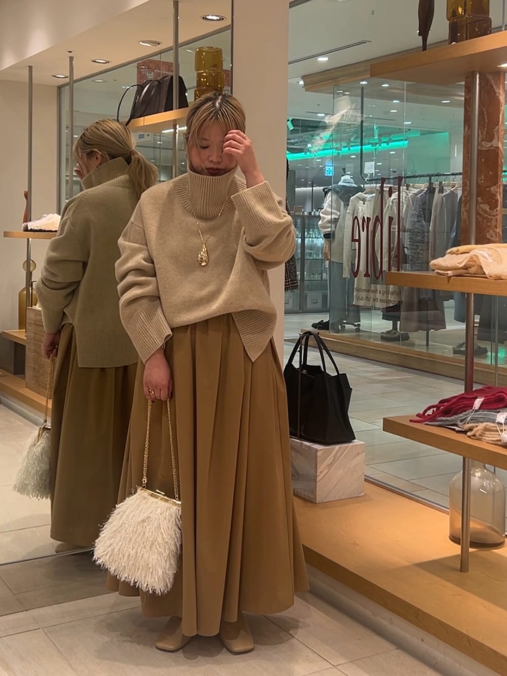 ベージュ系のニット/セーター、イエロー系のスカート、ホワイト系のショルダーバッグを着用したレディースの秋コーディネートの6枚目の写真