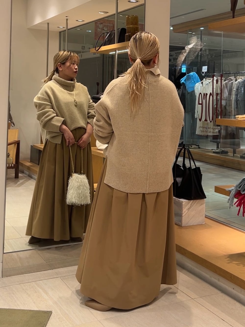 ベージュ系のニット/セーター、イエロー系のスカート、ホワイト系のショルダーバッグを着用したレディースの秋コーディネートの2枚目の写真