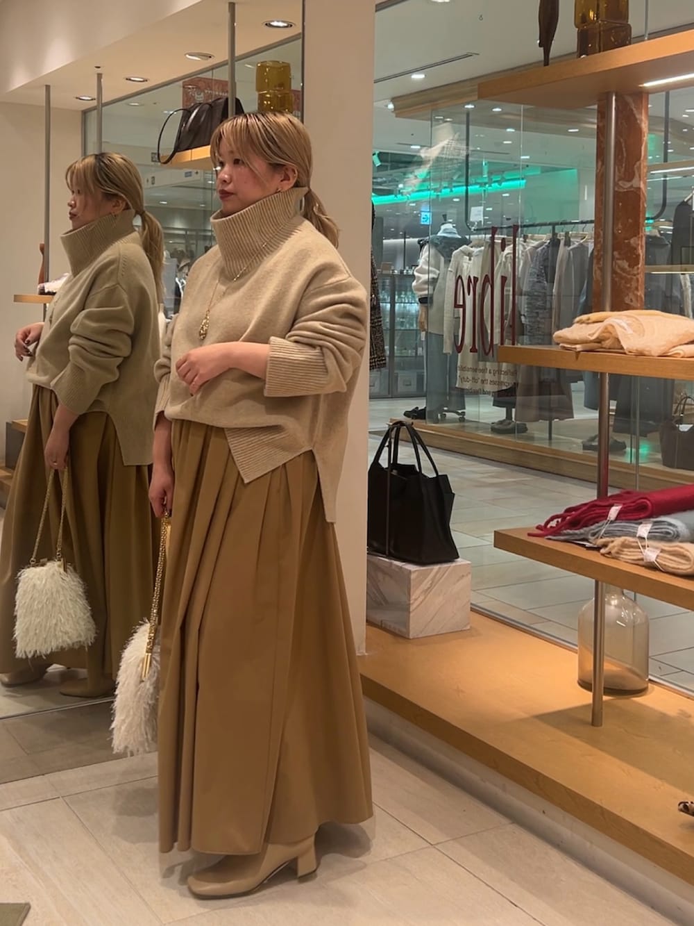 ベージュ系のニット/セーター、イエロー系のスカート、ホワイト系のショルダーバッグを着用したレディースの秋コーディネートの5枚目の写真