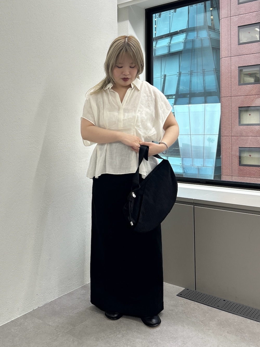 ブラック系のショルダーバッグ、ブラック系のスカート、ブラック系のローファーを着用したレディースの春コーディネートの4枚目の写真