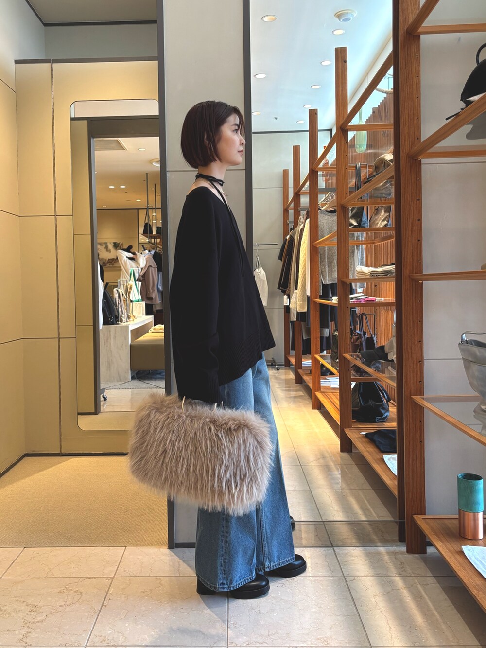 ブラック系のニット/セーター、ベージュ系のショルダーバッグ、ブルー系のデニムパンツを着用したレディースの秋コーディネートの2枚目の写真