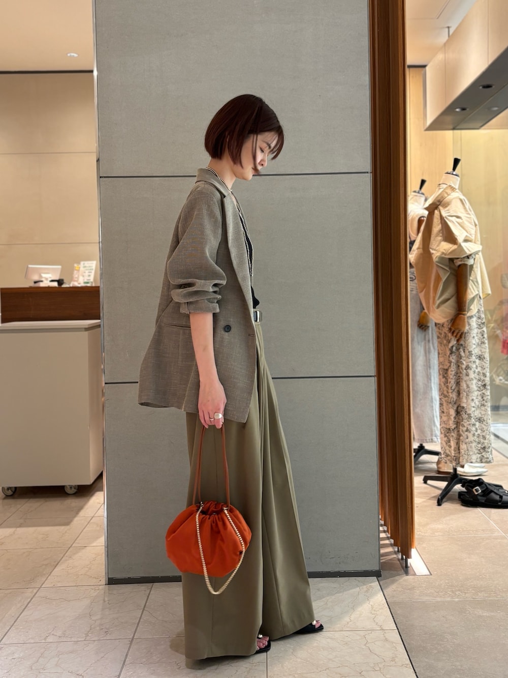 ベージュ系のその他パンツ、ブラック系のサンダル、オレンジ系のトートバッグを着用したレディースの春コーディネートの2枚目の写真