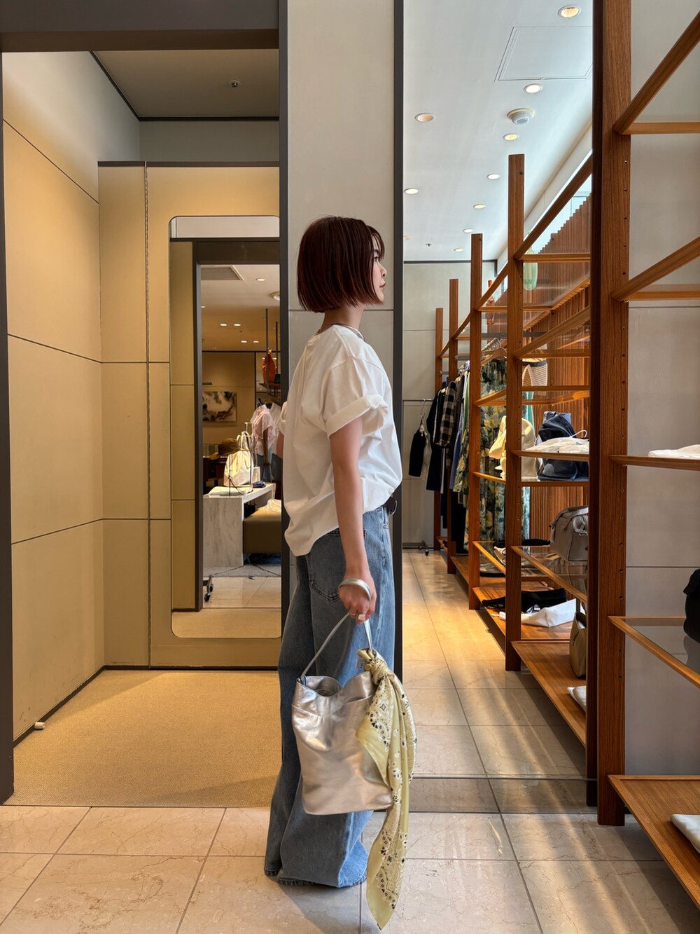 ブルー系のデニムパンツ、ホワイト系のTシャツ/カットソー、シルバー系のトートバッグを着用したレディースの春コーディネートの2枚目の写真