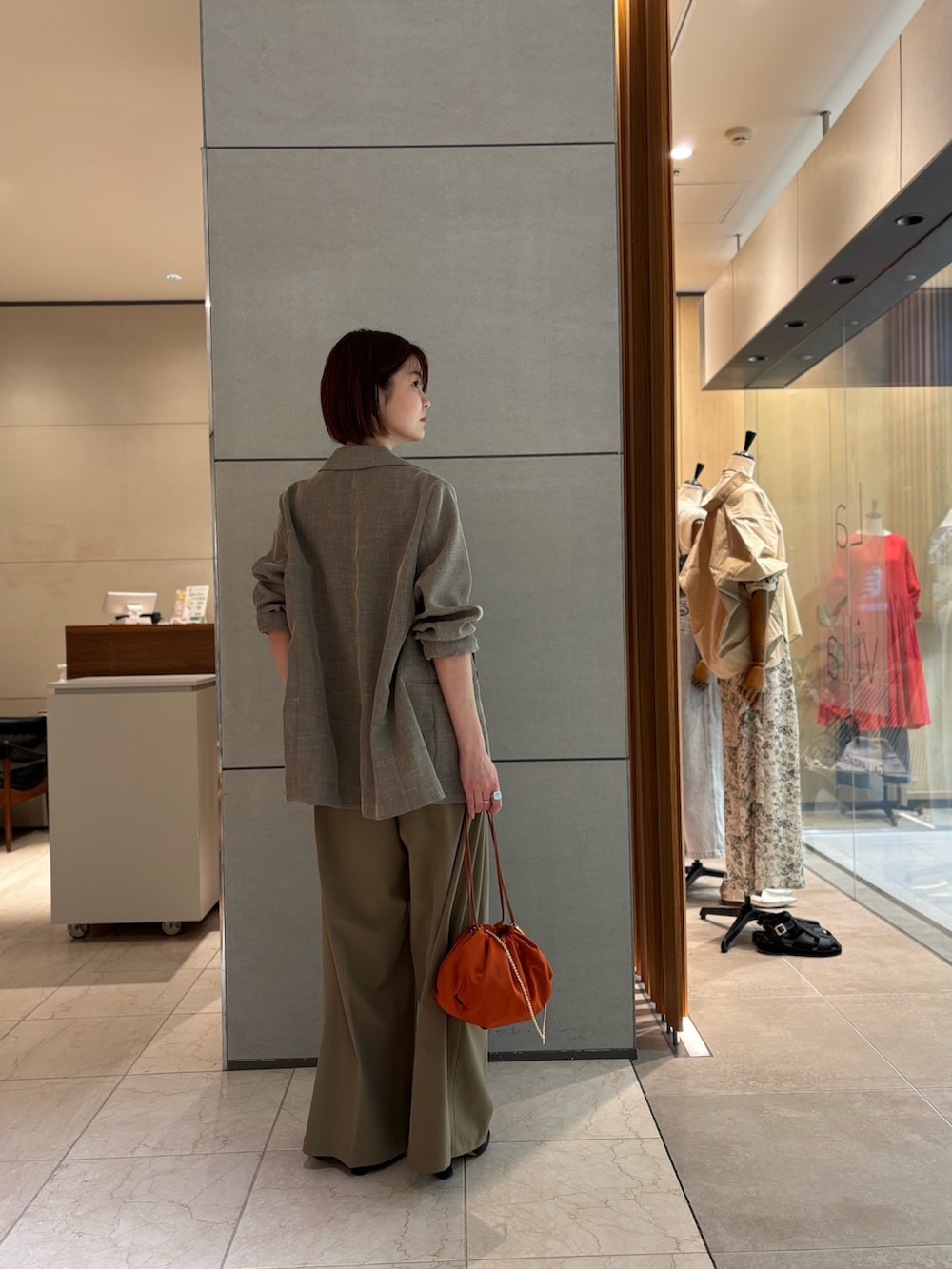 ベージュ系のその他パンツ、ブラック系のサンダル、オレンジ系のトートバッグを着用したレディースの春コーディネートの3枚目の写真