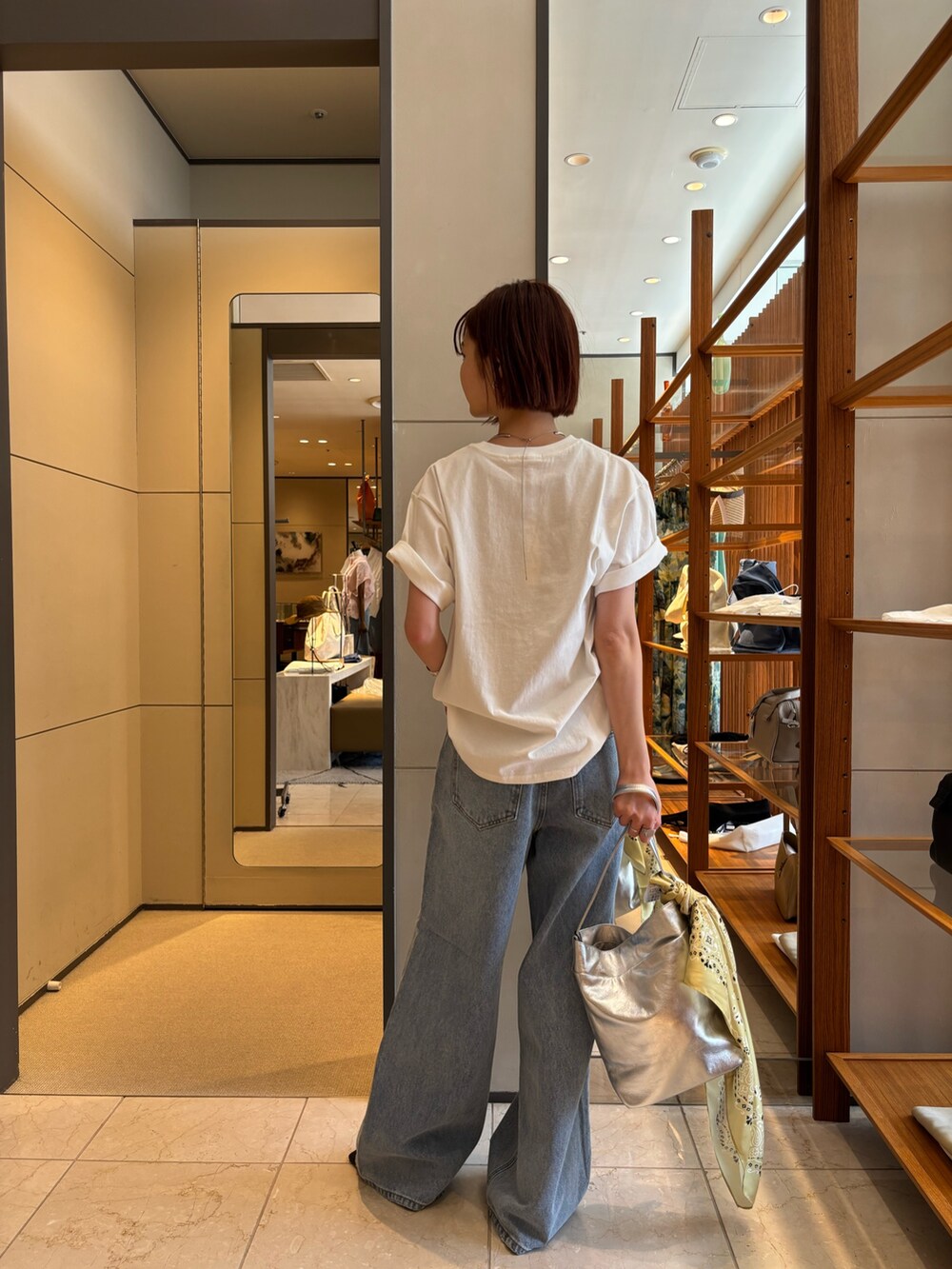 ブルー系のデニムパンツ、ホワイト系のTシャツ/カットソー、シルバー系のトートバッグを着用したレディースの春コーディネートの3枚目の写真