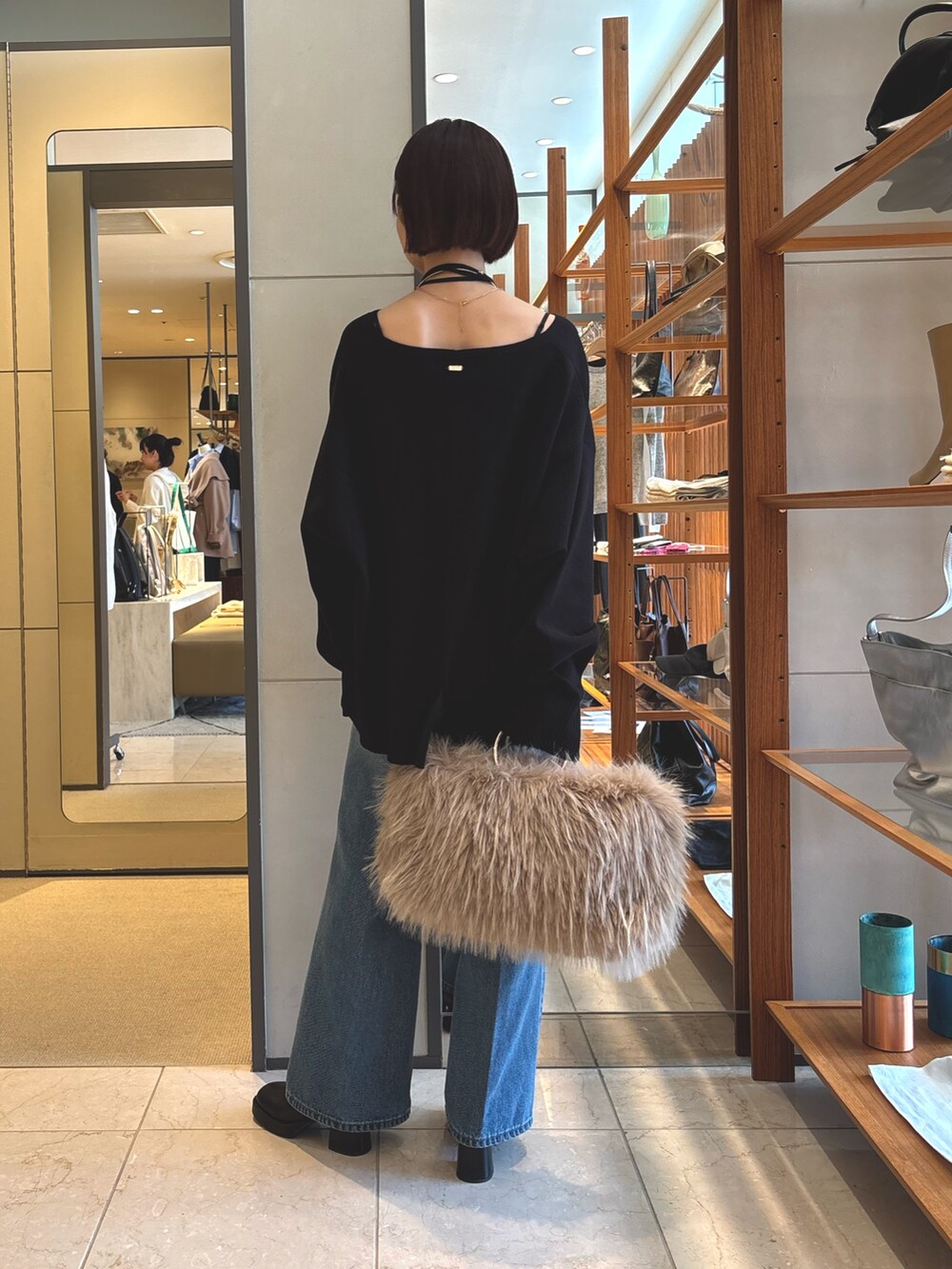 ブラック系のニット/セーター、ベージュ系のショルダーバッグ、ブルー系のデニムパンツを着用したレディースの秋コーディネートの3枚目の写真