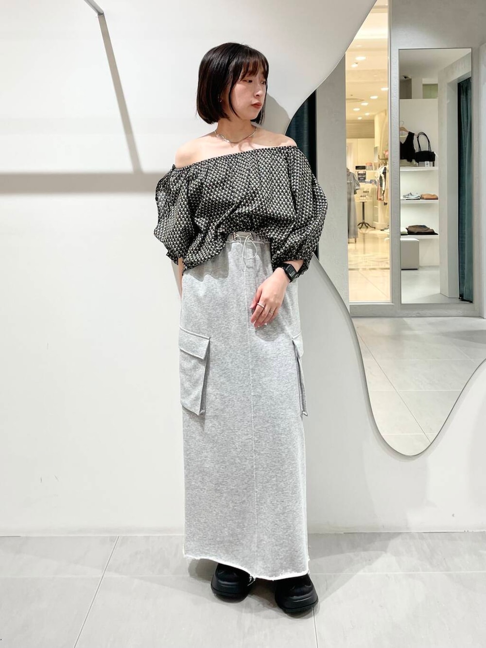 ブラック系のシャツ/ブラウス、グレー系のスカート、ブラック系のスニーカーを着用したレディースの夏コーディネートの3枚目の写真